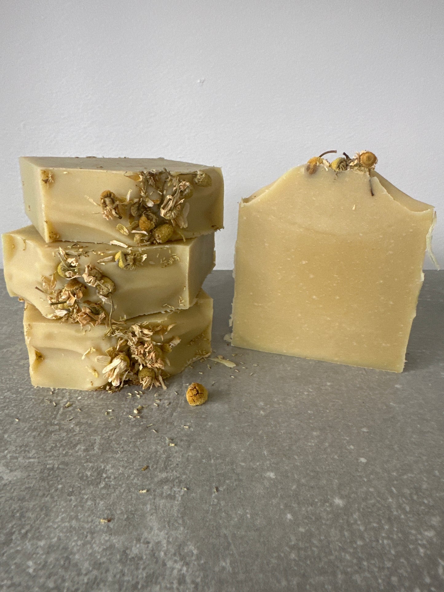 Two chamomile soap bars with chamomile flowers on a top