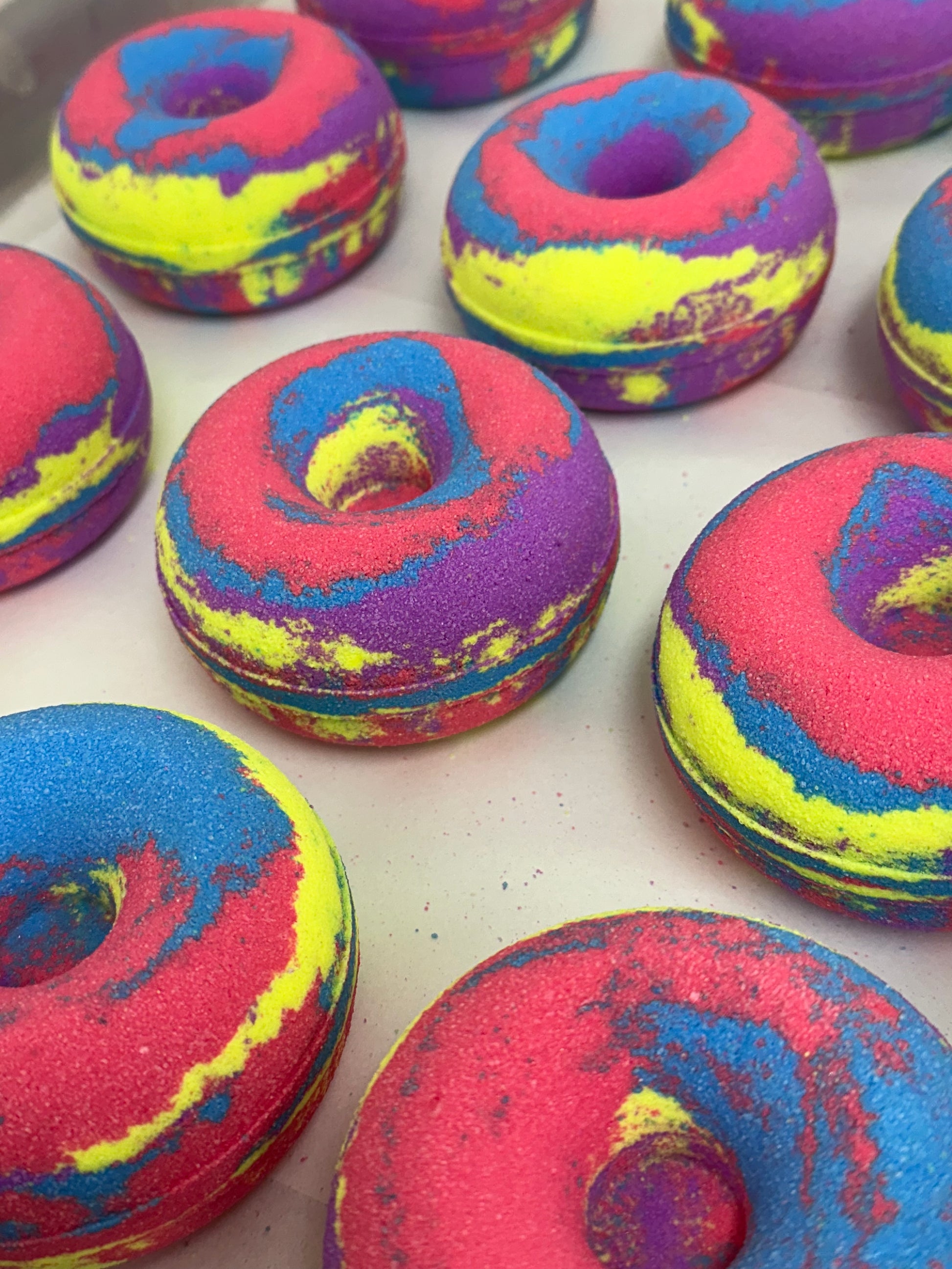 Colorful donut-shaped bath bombs on a white surface